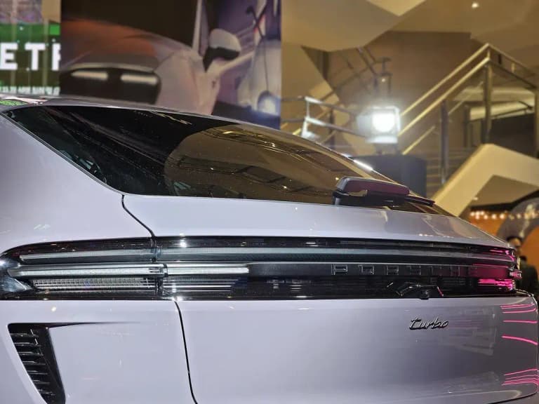 Rear detail of a Porsche Macan EV showing the illuminated Porsche script and light bar