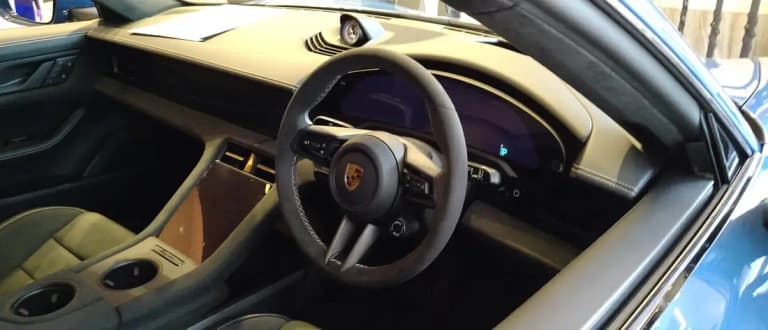 Porsche Taycan interior showing the steering wheel and curved digital driver display