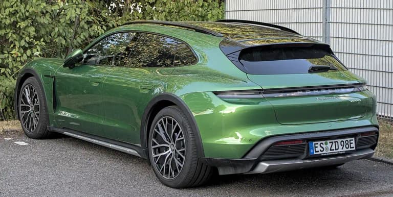 Green Porsche Taycan 4S Cross Turismo rear three-quarter view with roof rails and hatch spoiler