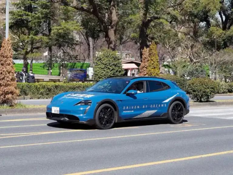 Blue Porsche Taycan Cross Turismo side profile on a road showing the long wagon roofline