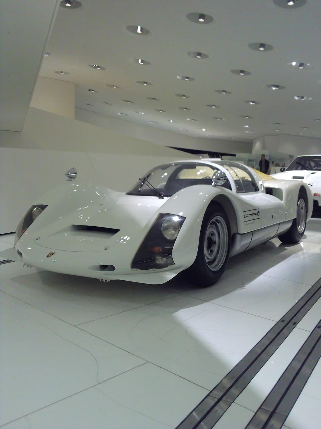 Front three-quarter view of a Porsche 906 Carrera 6 displayed at the Porsche Museum.
