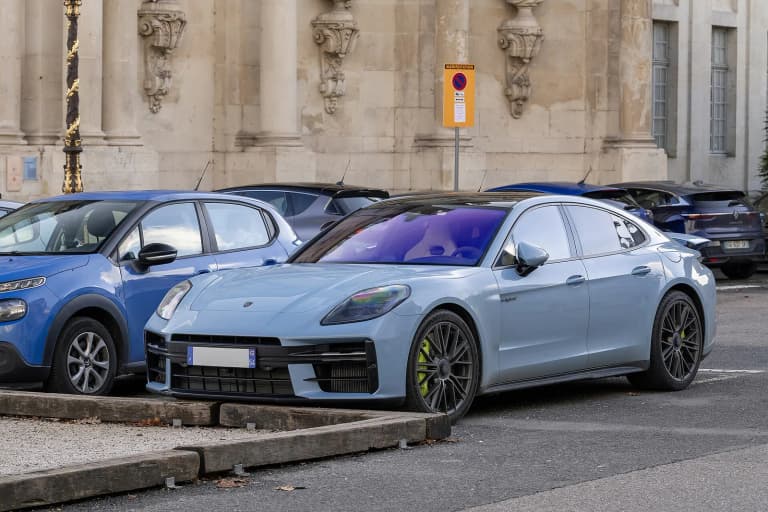 Light blue current-generation Porsche Panamera Turbo S E-Hybrid parked in a city street.