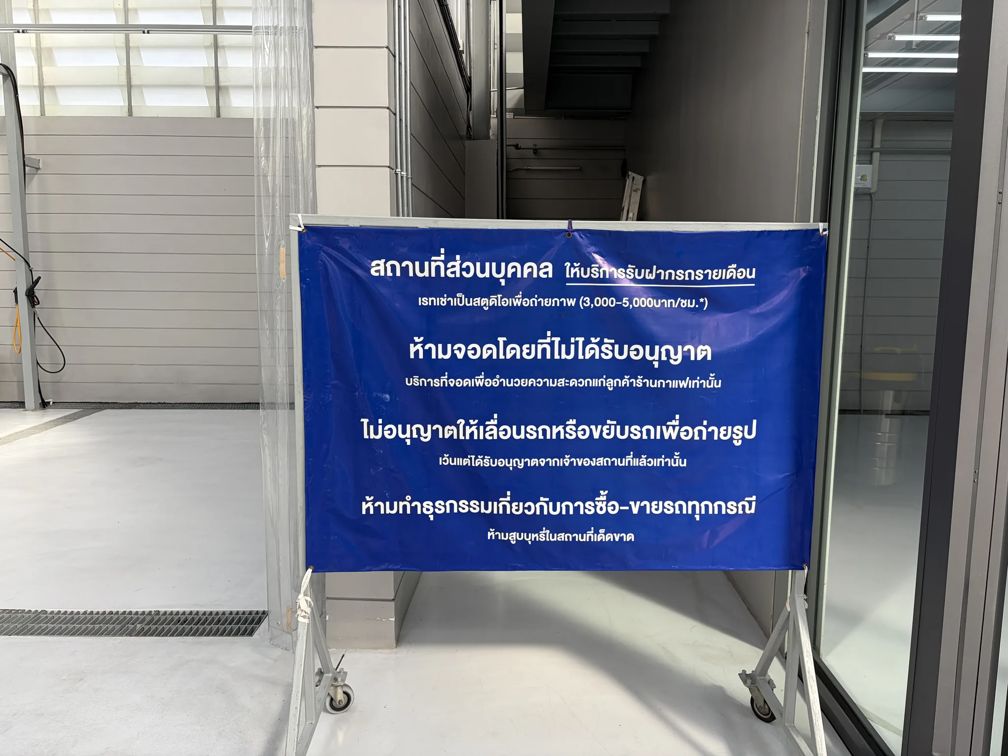 Thai notice sign beside an Archive Coffee garage stairwell