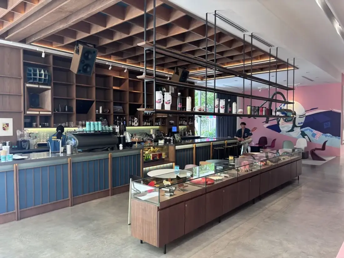 Coffee bar inside Curvistan Bangkok with a racing driver mural on the pink wall